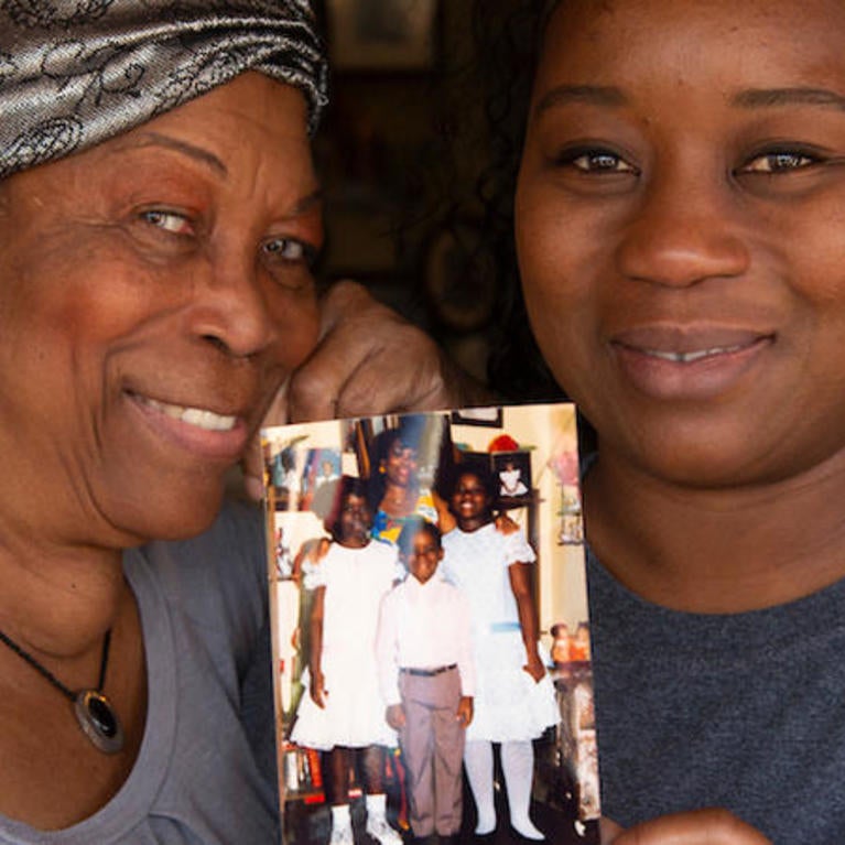 Deidre Reyes alongside her mother Sally Reyes holding a family photograph