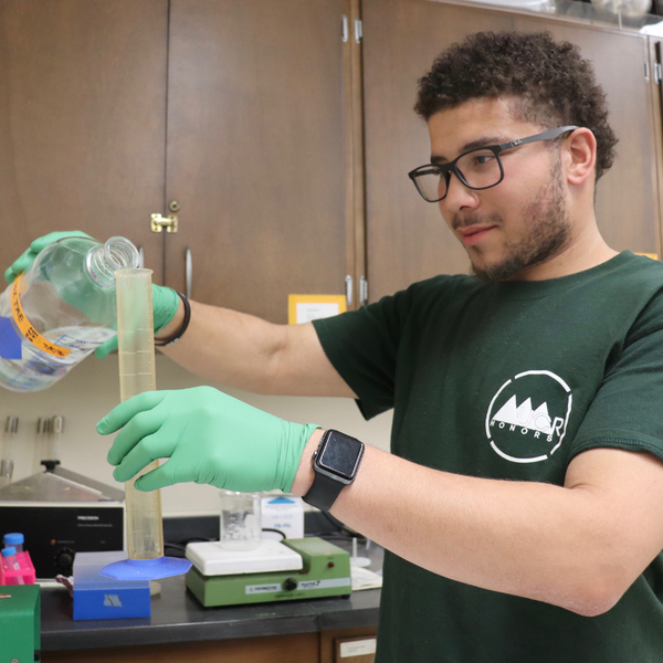 Student adding liquid to test tube in lab setting