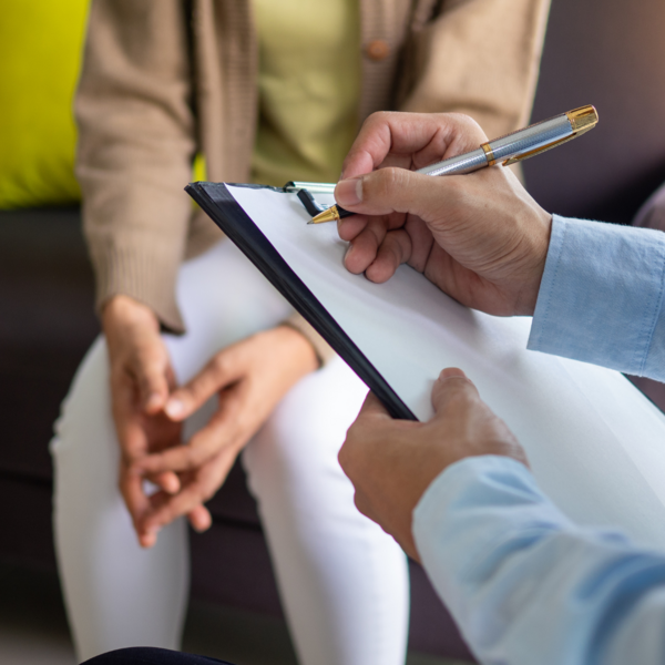 Individual taking notes during a counseling session