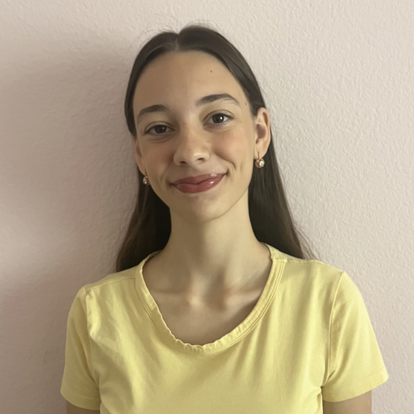 Woman wearing a light yellow short-sleeve top with a round neckline, standing against a plain background.