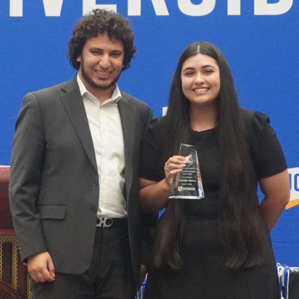 University Honors Valedictorian Jennifer Ibarra posing with University Honors Alum Mina Hanin and her valedictory award